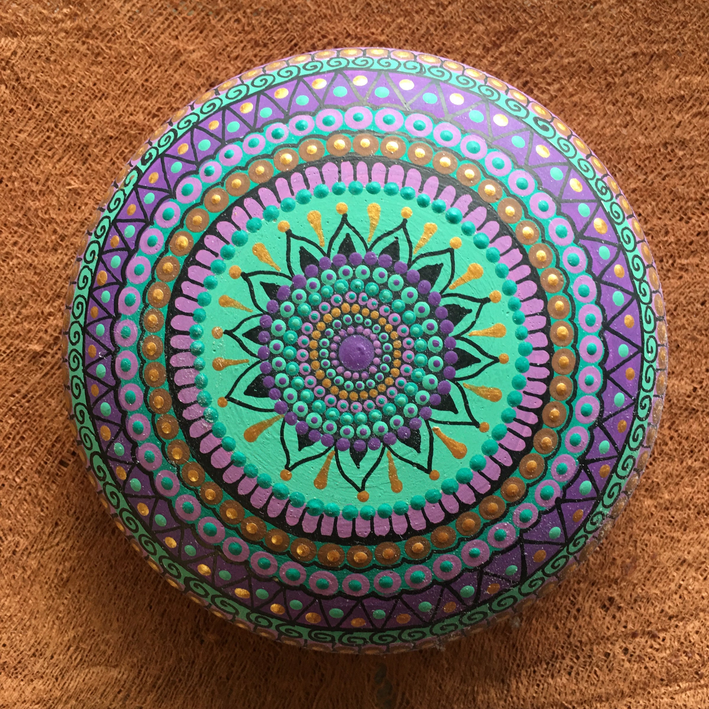 Large mandala stone on a sandy background with some plants