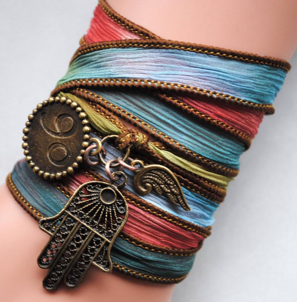 silk wrap bracelet in blue, red and green with a hamsa charm, a wing charm.