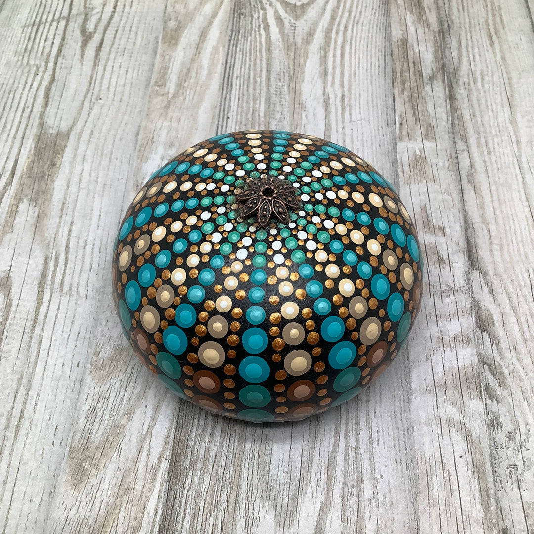 Sphere-shaped stone with painted Sea Urchin design and an antique gold-colored ornament on top.