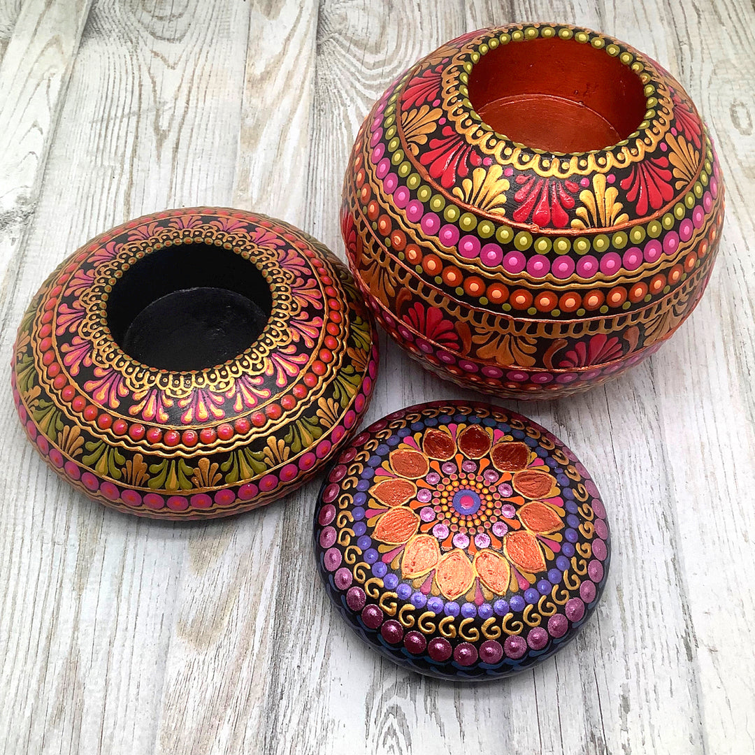 a painted mandala stone in purple,pink and orange and two painted tealight holders with mandala design in pink orange and gold