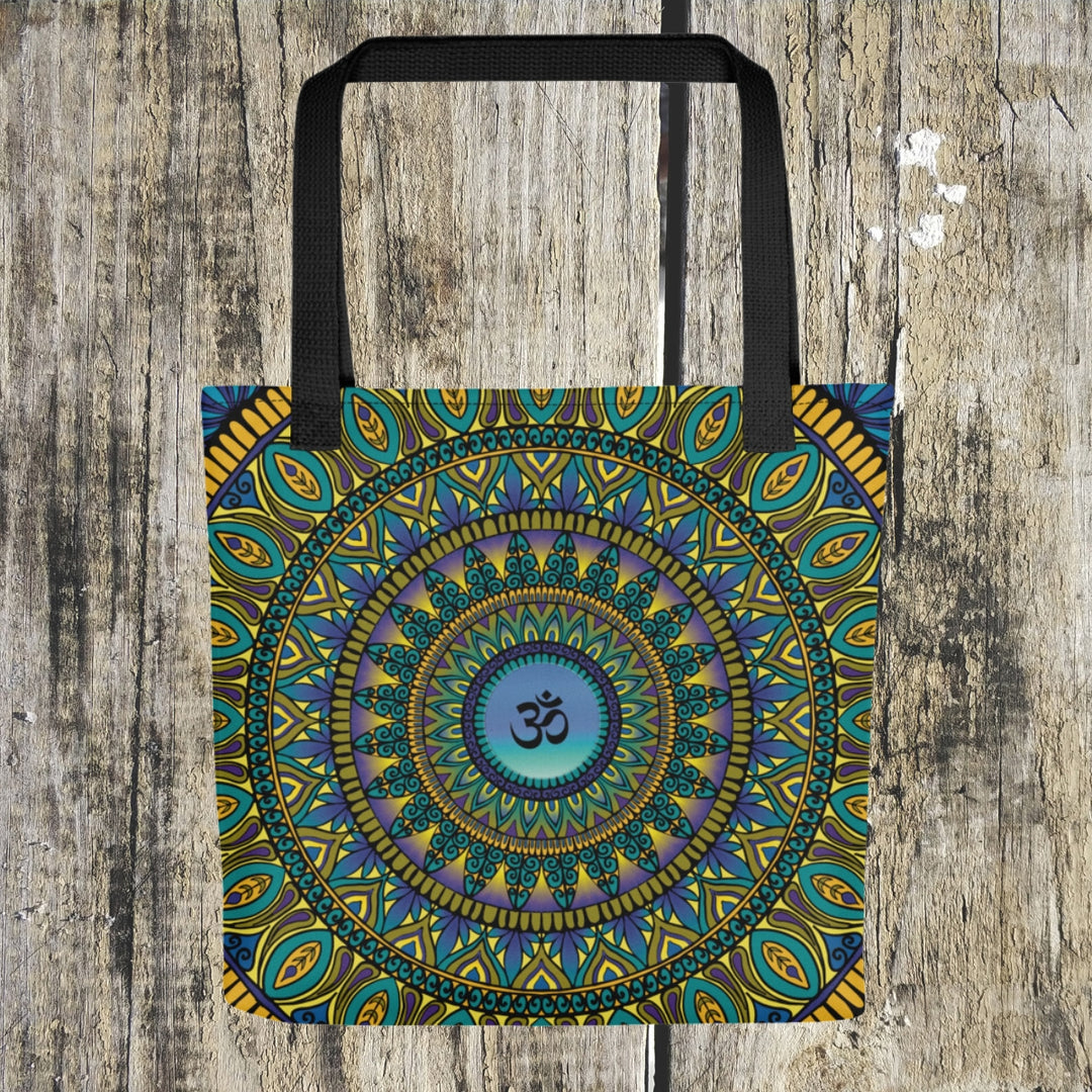 A mandala tote bag in Petrol, Purple, and Gold colors with an Ohm symbol, symbolizing serenity and spirituality.